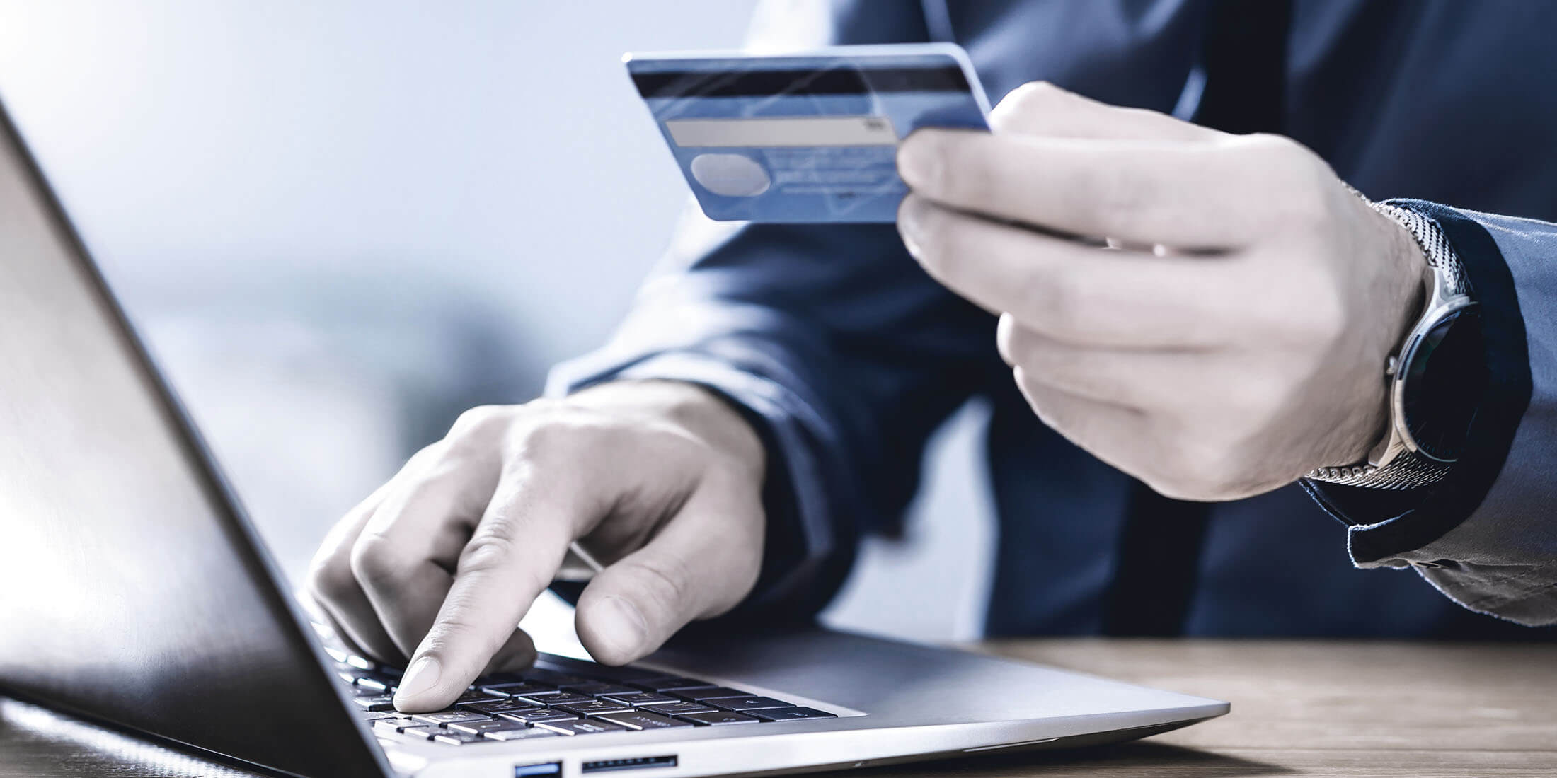 Man holding credit card in front of computer